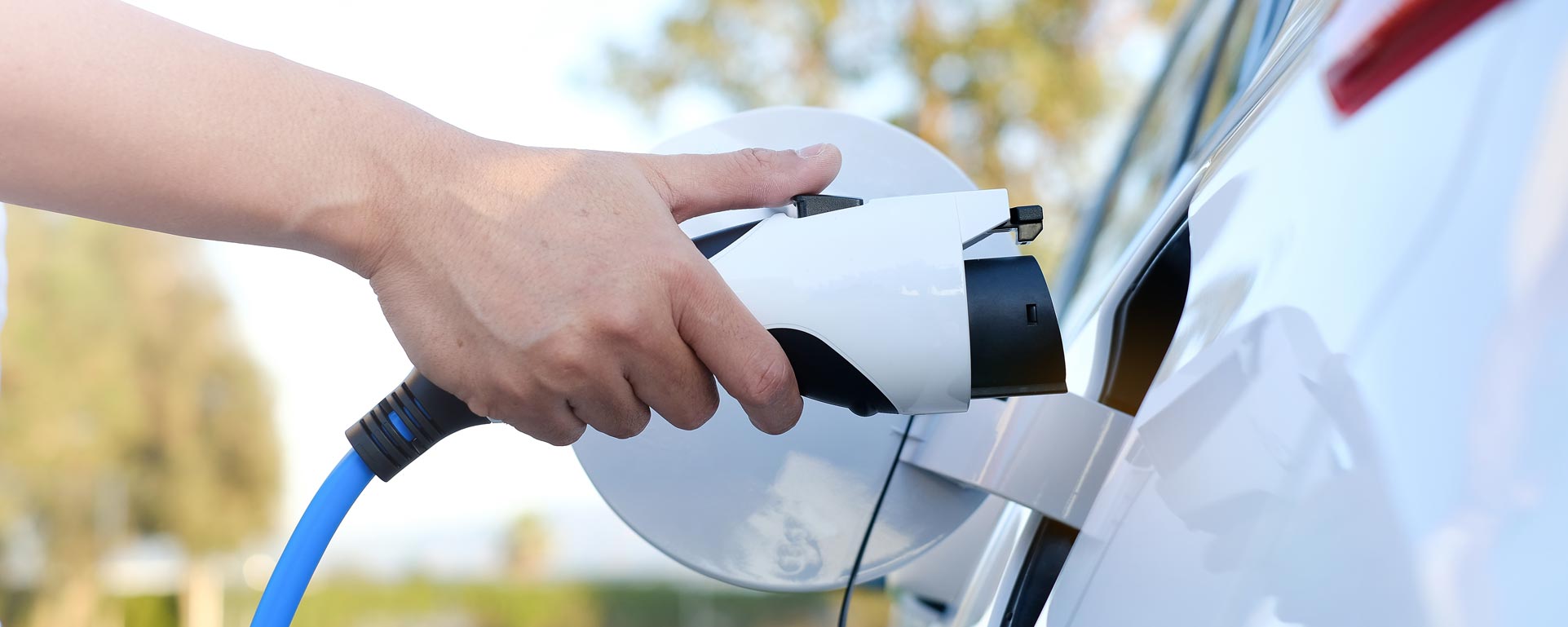 closeup of person's hand plugging in electric vehicle to charge