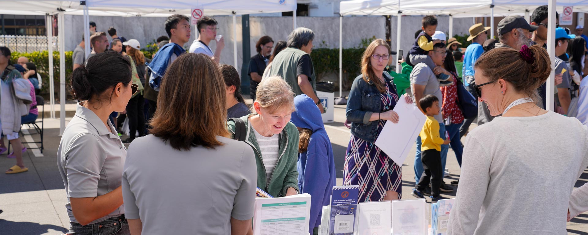 community member looking at brochures at event outreach table hosted by Sustainability Department staff